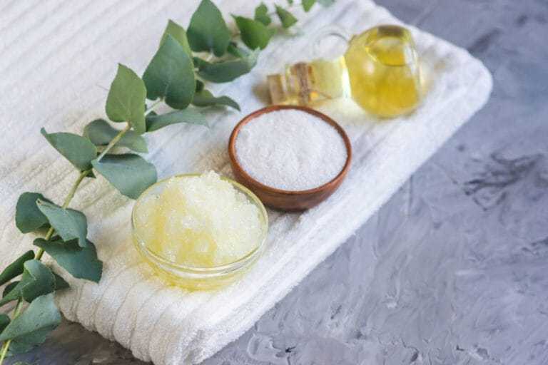 Eucalyptus, bath salts, and oil set on a towel for a spa experience.