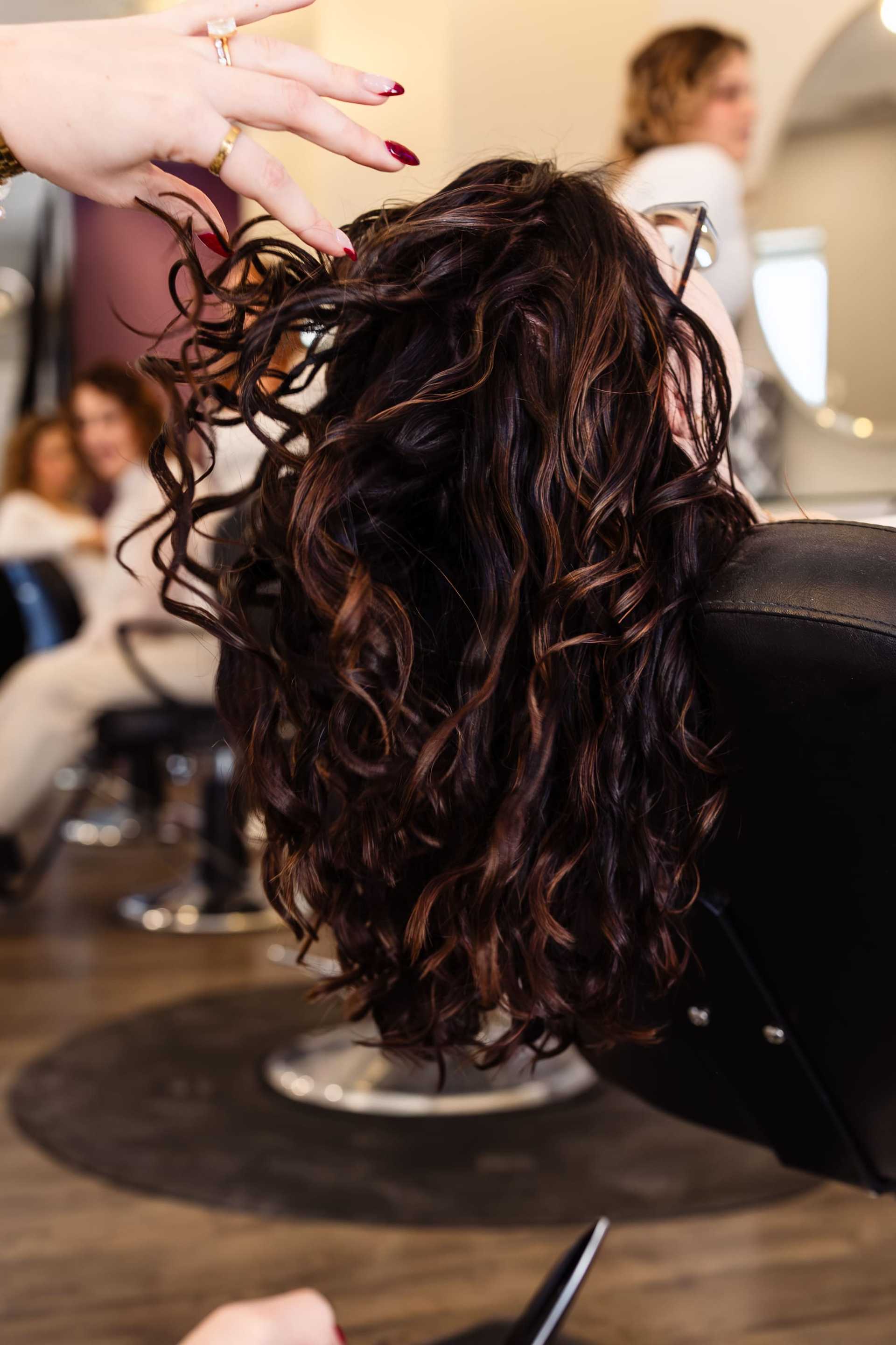 Curly hair being styled at a salon, with focus on vibrant, wavy locks.