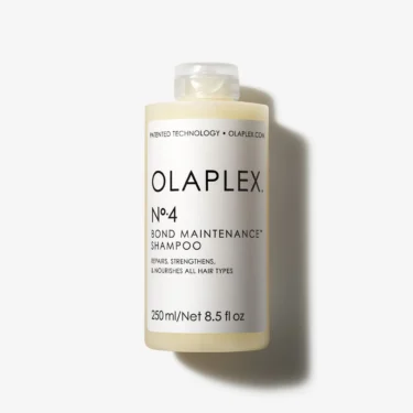 Close-up of a cream-colored bottle with a white label that says Olaplex Number 4 Bond Maintenance Shampoo.